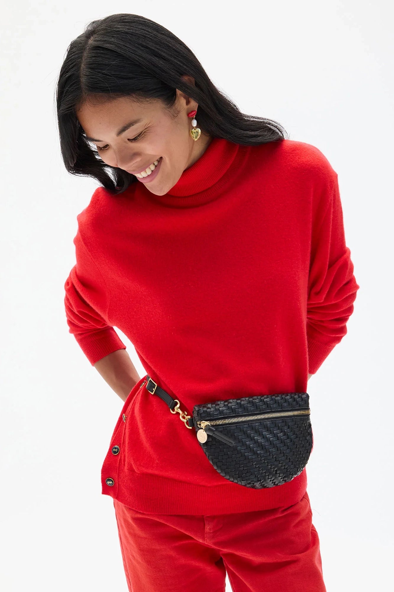 Woman wearing a red outfit with a black fanny pack on a white background
