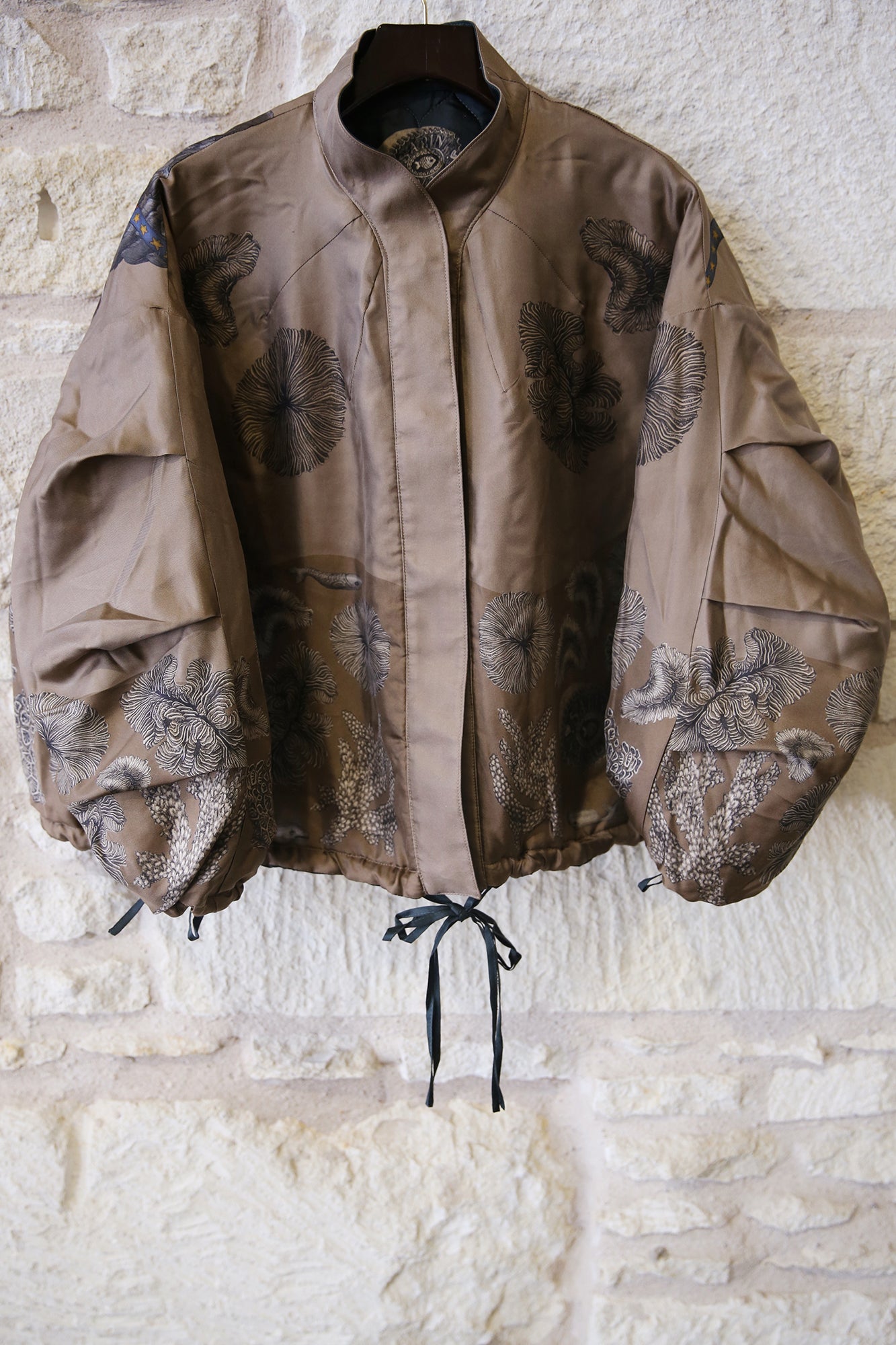 Brown jacket with floral patterns on a stone wall background